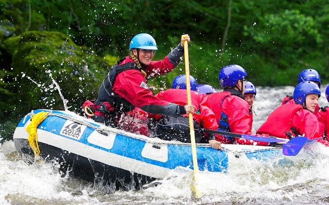 Crew of people laughing and enjoying whitewater rafting